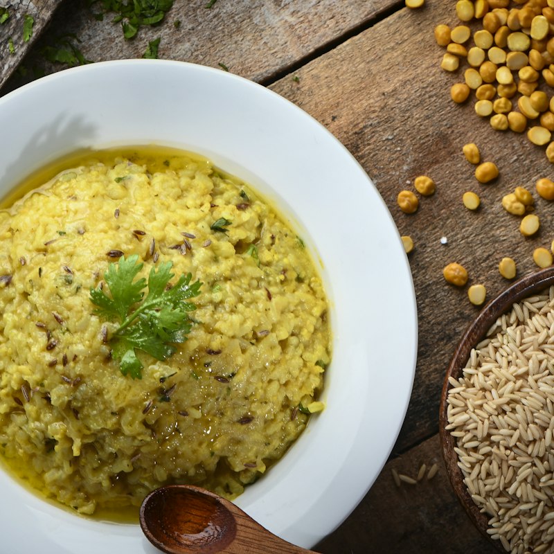 A bowl of daal mash, pale and thick, scattered with cumin seeds and topped with coriander