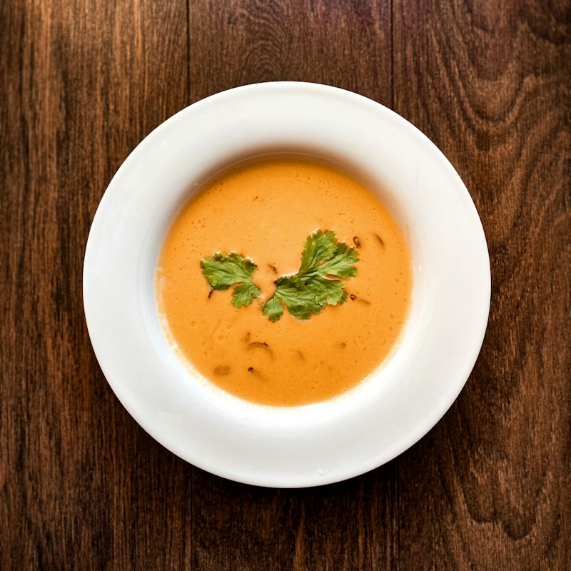 A bowl of daal masoor, deep orange and smooth, topped with fresh coriander